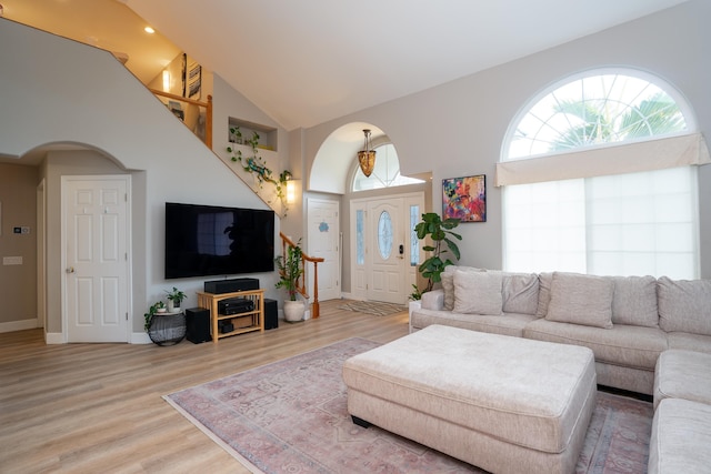 living room featuring high vaulted ceiling and light hardwood / wood-style flooring