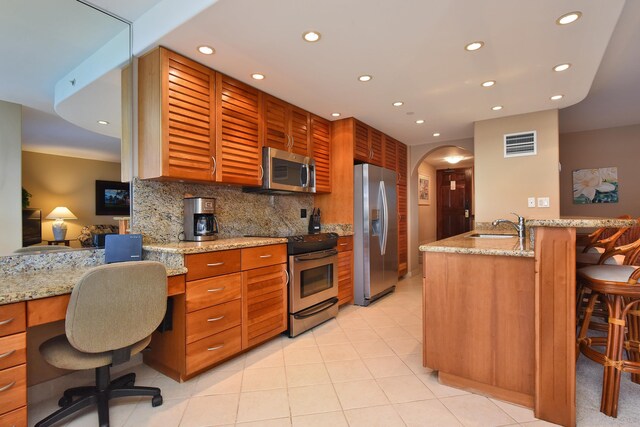 kitchen with kitchen peninsula, appliances with stainless steel finishes, tasteful backsplash, and a breakfast bar