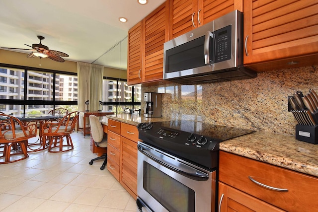 kitchen featuring decorative backsplash, light stone countertops, stainless steel appliances, and ceiling fan