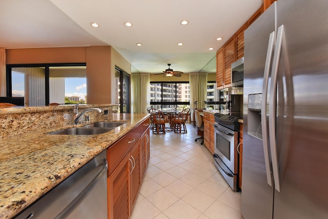 kitchen featuring light stone countertops, appliances with stainless steel finishes, sink, ceiling fan, and light tile patterned flooring