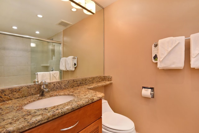 bathroom featuring toilet, an enclosed shower, and vanity