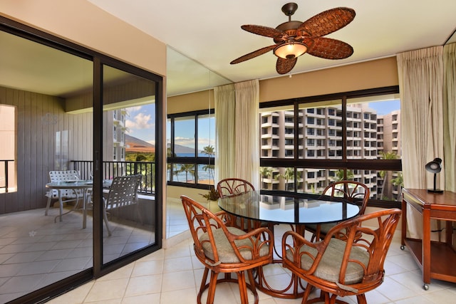 tiled dining room featuring wooden walls and ceiling fan