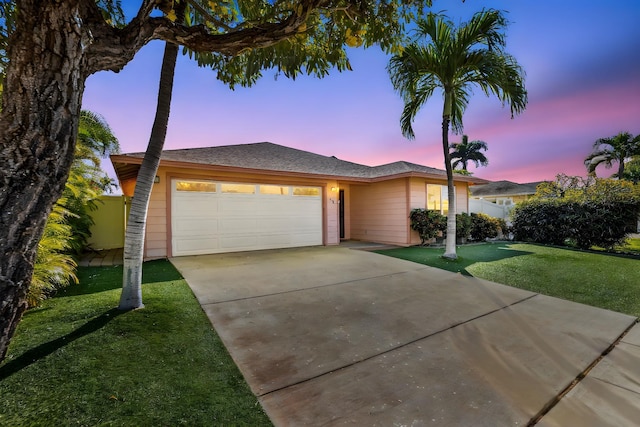 view of front of home featuring a yard, driveway, an attached garage, and fence