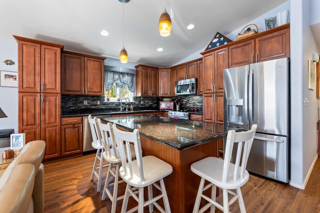 kitchen featuring lofted ceiling, a kitchen breakfast bar, a sink, stainless steel appliances, and backsplash