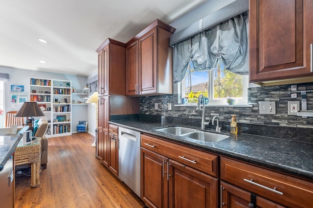 kitchen with dark stone counters, a sink, decorative backsplash, dishwasher, and light wood finished floors