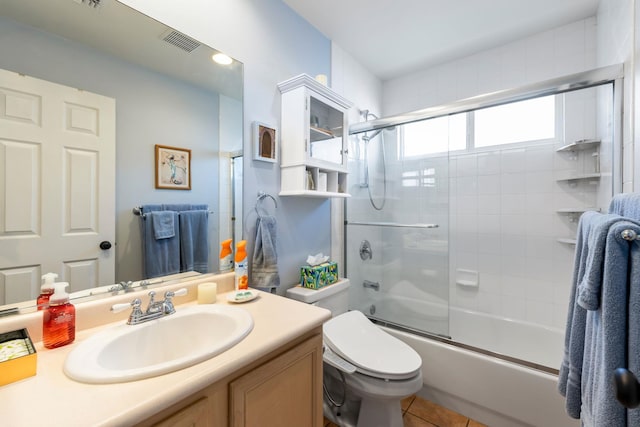 bathroom featuring shower / bath combination with glass door, visible vents, toilet, vanity, and tile patterned floors