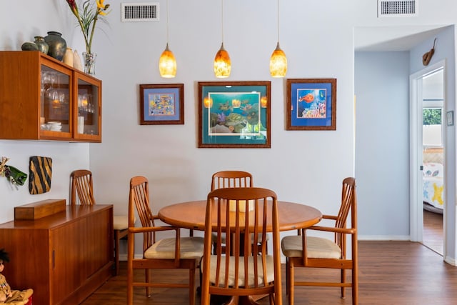 dining area featuring dark wood-style flooring, visible vents, and baseboards