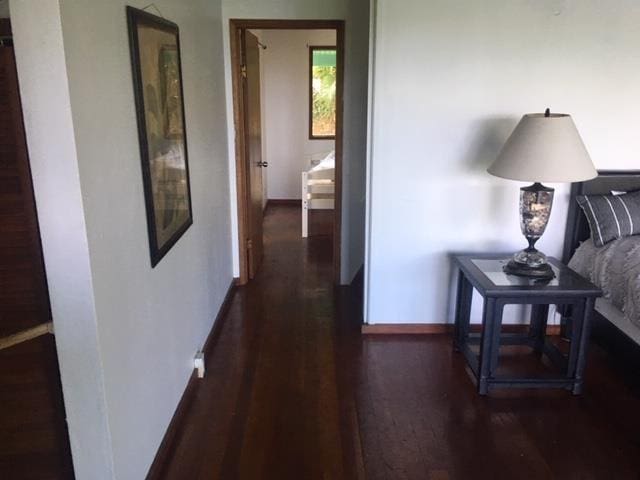 hallway with dark wood-type flooring and baseboards