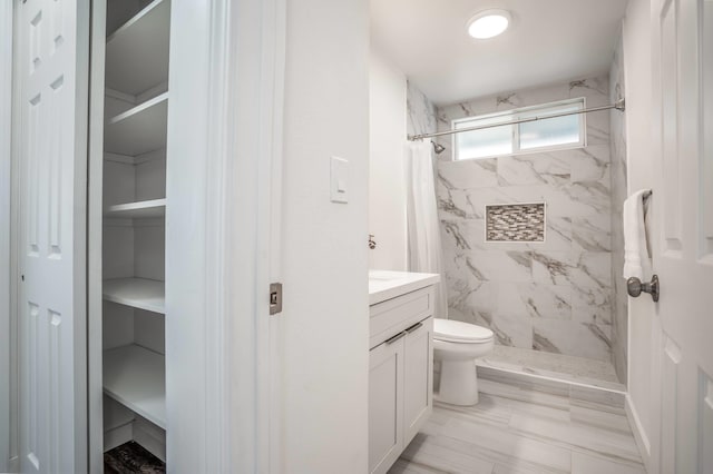 bathroom with toilet, vanity, and tiled shower