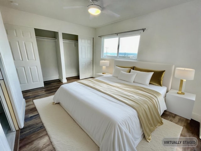 bedroom with dark wood-type flooring, ceiling fan, and multiple closets