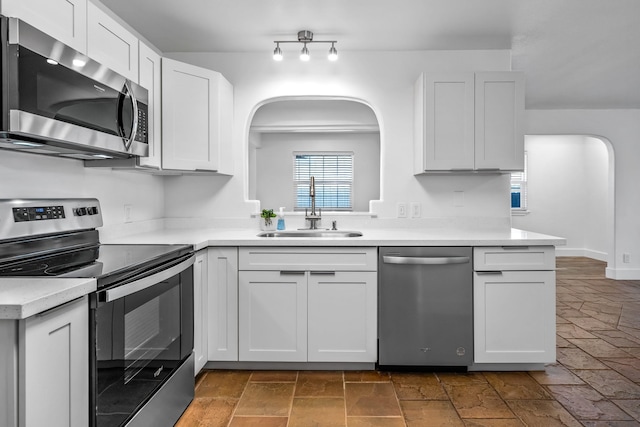 kitchen with white cabinetry, kitchen peninsula, appliances with stainless steel finishes, and sink