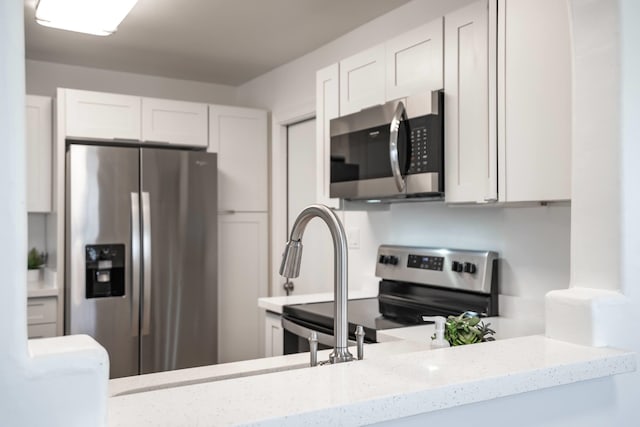 kitchen featuring white cabinetry, light stone counters, and stainless steel appliances