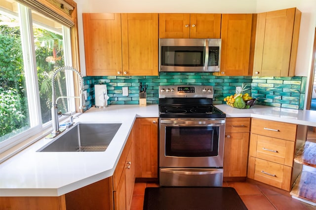 kitchen with appliances with stainless steel finishes, sink, a wealth of natural light, and tasteful backsplash