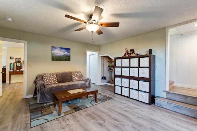 living room with light hardwood / wood-style floors, wood walls, and a textured ceiling