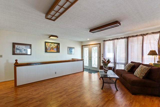 living room with french doors, a textured ceiling, and hardwood / wood-style flooring