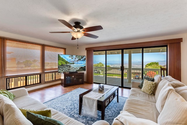 living room featuring light hardwood / wood-style flooring, a textured ceiling, and ceiling fan