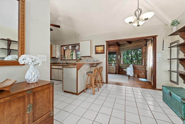 kitchen featuring a kitchen bar, kitchen peninsula, light tile patterned flooring, pendant lighting, and white cabinets