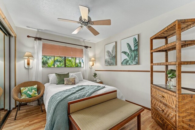 bedroom with ceiling fan, a textured ceiling, light hardwood / wood-style flooring, and a closet