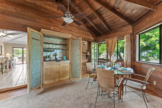 dining space with light carpet, wooden walls, wooden ceiling, ceiling fan, and vaulted ceiling with beams