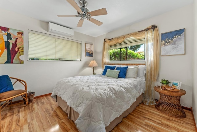 bedroom with an AC wall unit, light hardwood / wood-style floors, and ceiling fan