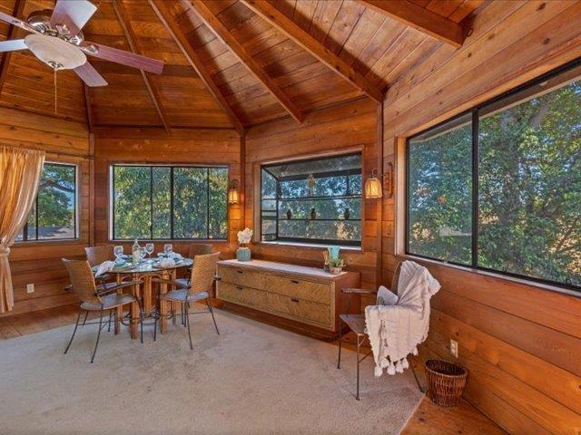 living area with hardwood / wood-style floors, lofted ceiling with beams, an inviting chandelier, wooden walls, and wooden ceiling