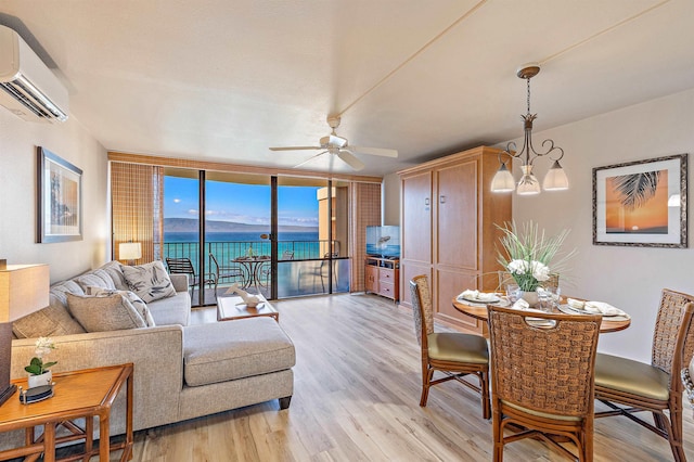 living room featuring a wall unit AC, ceiling fan with notable chandelier, floor to ceiling windows, and light hardwood / wood-style flooring