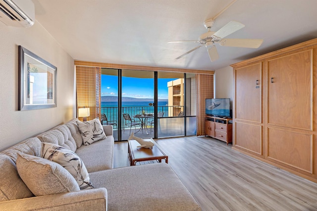 living room featuring ceiling fan, light hardwood / wood-style floors, floor to ceiling windows, and a wall mounted air conditioner