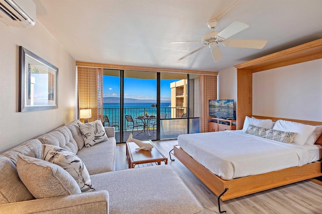 bedroom with ceiling fan, access to exterior, floor to ceiling windows, hardwood / wood-style floors, and a wall unit AC