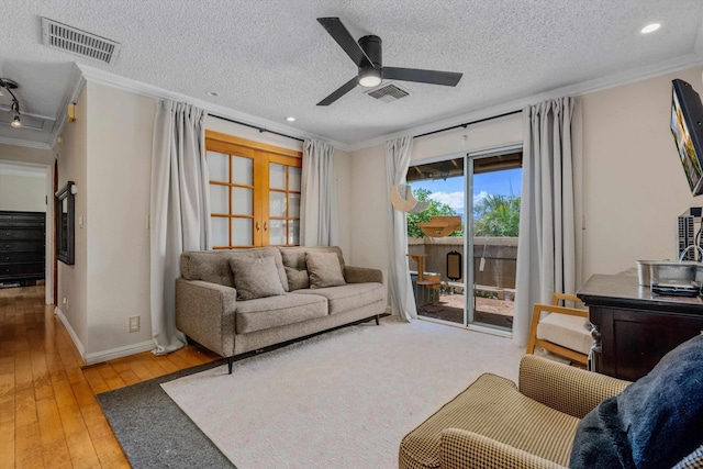 living room with hardwood / wood-style flooring, a textured ceiling, french doors, and ornamental molding