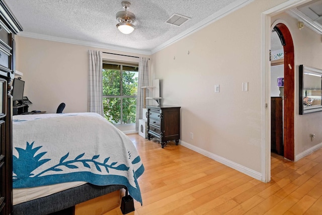 bedroom featuring ceiling fan, a textured ceiling, hardwood / wood-style flooring, and crown molding