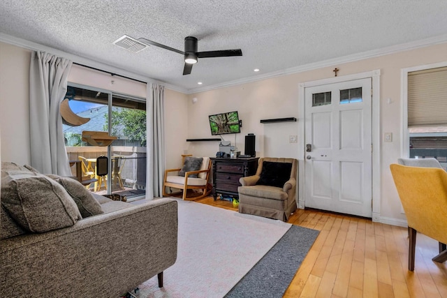 living room with hardwood / wood-style flooring, a textured ceiling, ceiling fan, and ornamental molding