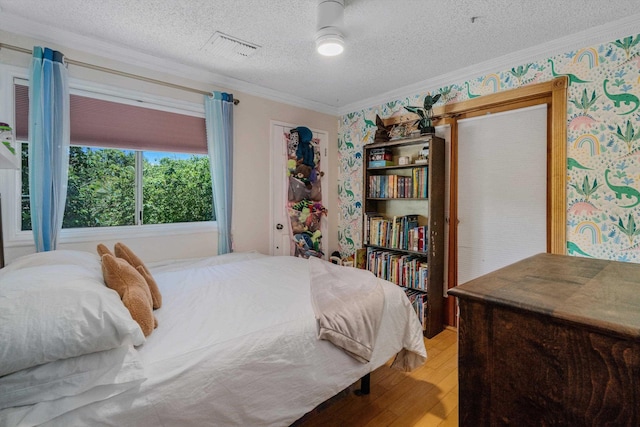 bedroom with hardwood / wood-style flooring, a textured ceiling, and crown molding