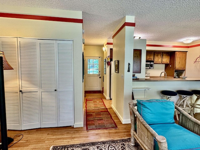 interior space with kitchen peninsula, a textured ceiling, and light wood-type flooring