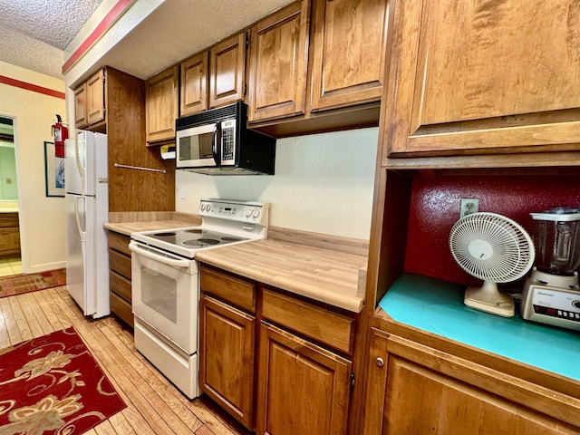 kitchen with white appliances, a textured ceiling, and light hardwood / wood-style flooring