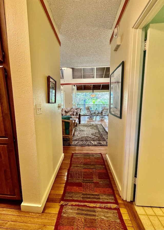 hallway with a textured ceiling and hardwood / wood-style flooring