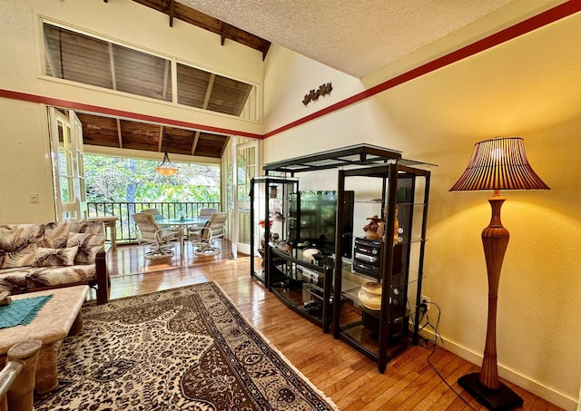 living room featuring a towering ceiling, hardwood / wood-style floors, and a textured ceiling