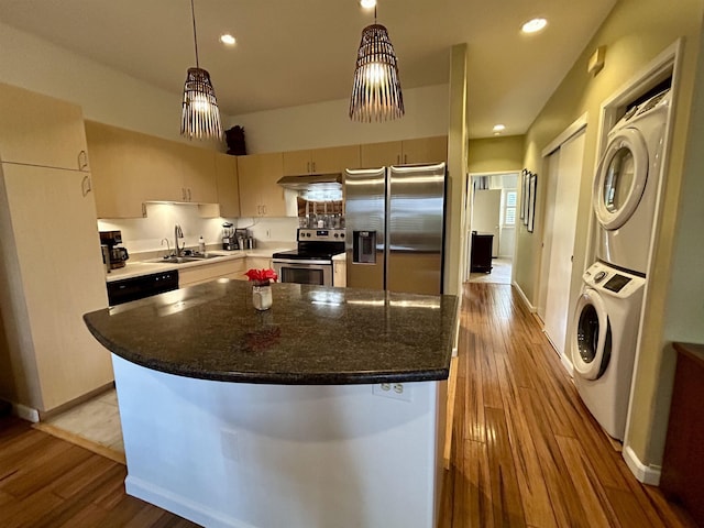 kitchen featuring stacked washer and clothes dryer, stainless steel appliances, light wood-style floors, and a sink