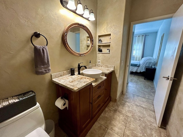 bathroom featuring connected bathroom, vanity, and a textured wall