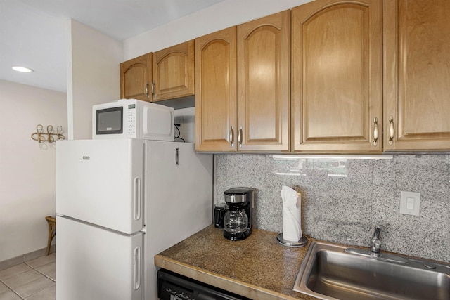 kitchen with light tile patterned floors, white appliances, a sink, baseboards, and backsplash