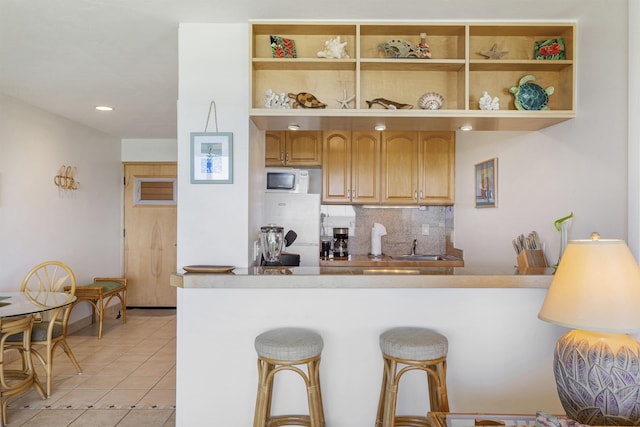 kitchen with open shelves, light tile patterned floors, tasteful backsplash, and a kitchen breakfast bar