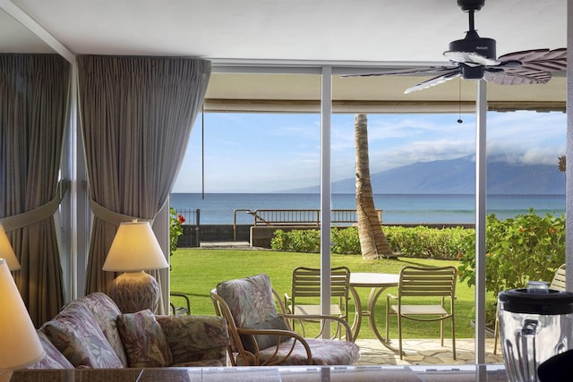 sunroom / solarium featuring a water view and ceiling fan