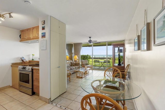 kitchen featuring stainless steel electric range, light tile patterned floors, open floor plan, a wall of windows, and baseboards