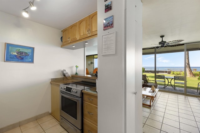 kitchen featuring light tile patterned floors, baseboards, a ceiling fan, rail lighting, and stainless steel electric stove