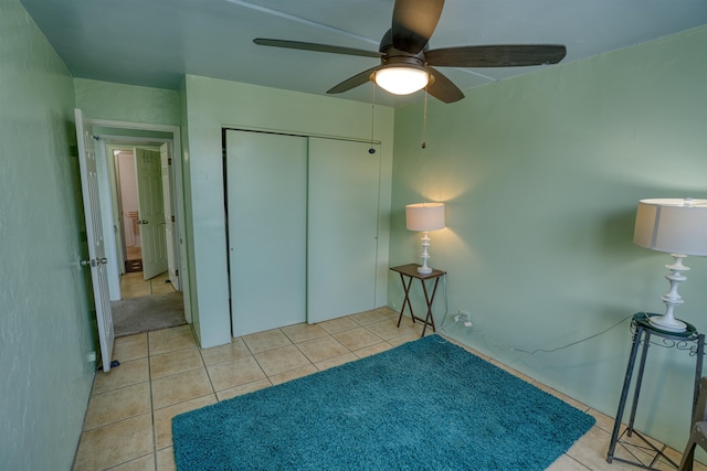 unfurnished bedroom featuring light tile patterned floors, ceiling fan, and a closet