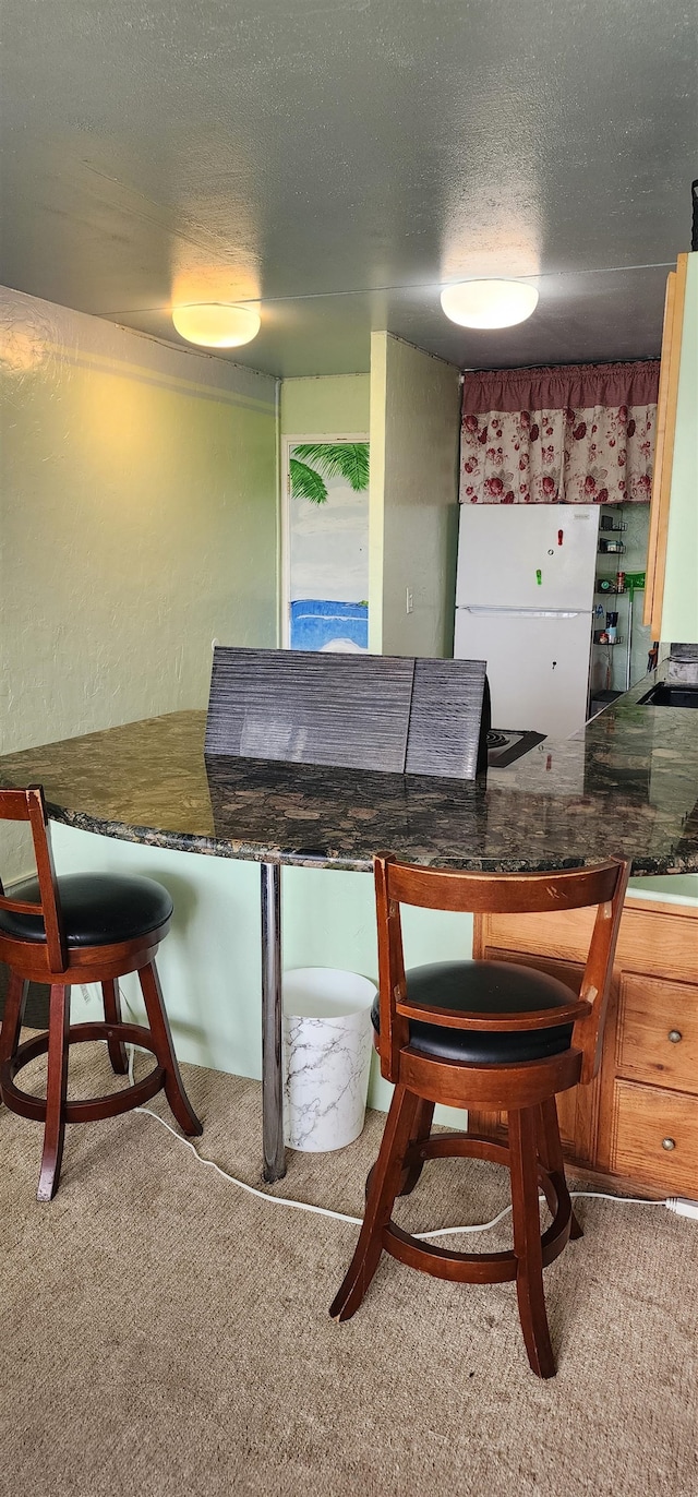 carpeted dining room with a textured ceiling