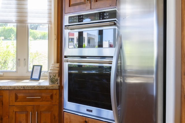 kitchen with brown cabinetry, plenty of natural light, stainless steel appliances, and light countertops