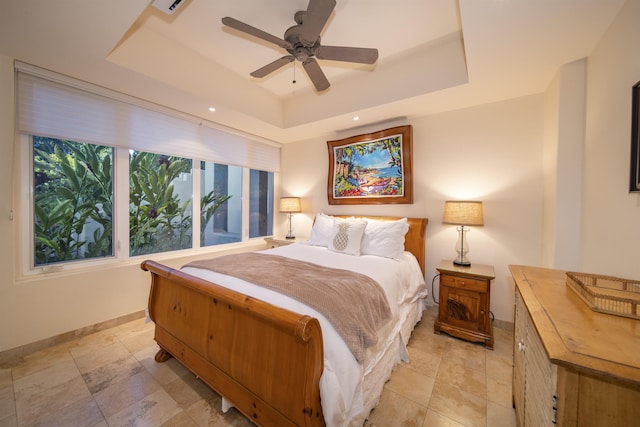 bedroom featuring a raised ceiling, ceiling fan, and baseboards