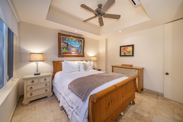 bedroom with a raised ceiling, ceiling fan, and baseboards