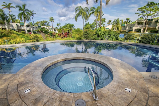 community pool with a residential view and a hot tub