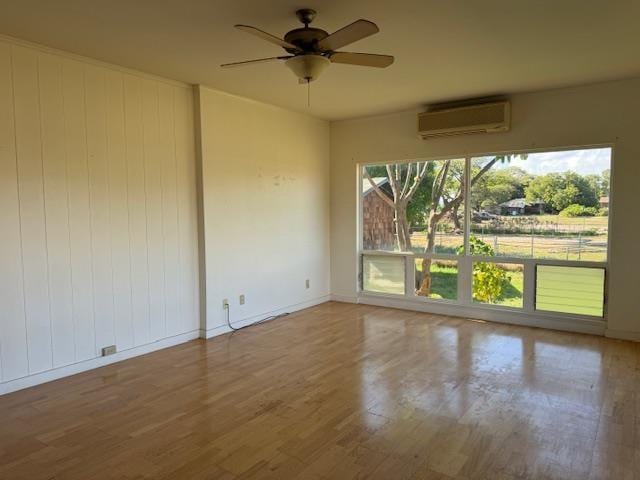 unfurnished room with a wall mounted air conditioner, ceiling fan, and wood-type flooring